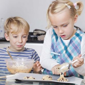 Happy brother and sister baking cookies in kitchen