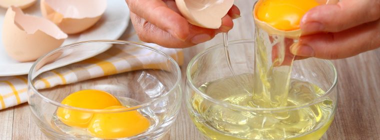 Woman hands breaking an egg to separate three eggs into two bowls and egg shells at background