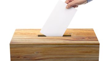 Ballot box with person casting vote on blank voting slip