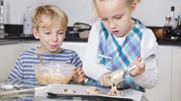 Happy brother and sister baking cookies in kitchen