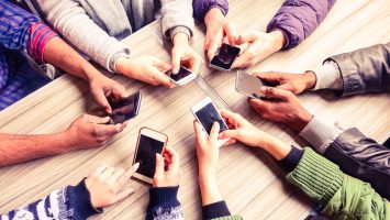 Top view hands circle using phone in cafe - Multiracial friends mobile addicted interior scene from above - Wifi Connected people in bar table meeting - Concept of teamwork main focus on left phones