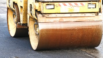 Compact steamroller flatten out the asphalt. Heavy Vibration roller at asphalt pavement works. Fragment of roller wheel, urban road is under construction, asphalting in progress.